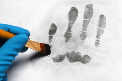 Photo of Criminalist taking fingerprints with brush from light surface, closeup. Forensic investigation