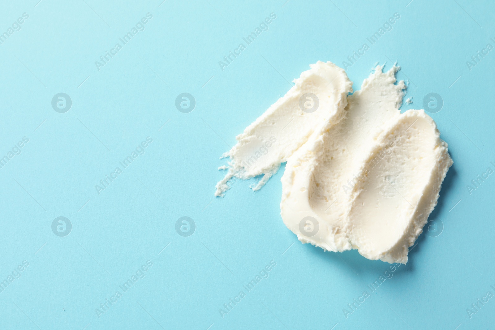 Photo of Smear of tasty cream cheese on color background, top view. Space for text