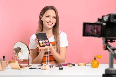 Photo of Beauty blogger filming make up tutorial on pink background