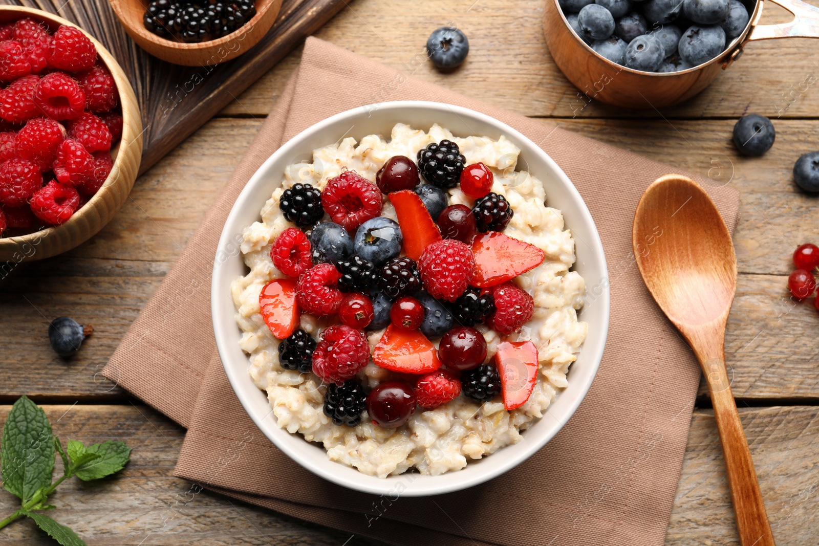 Photo of Flat lay composition with tasty oatmeal porridge and ingredients served on wooden table. Healthy meal