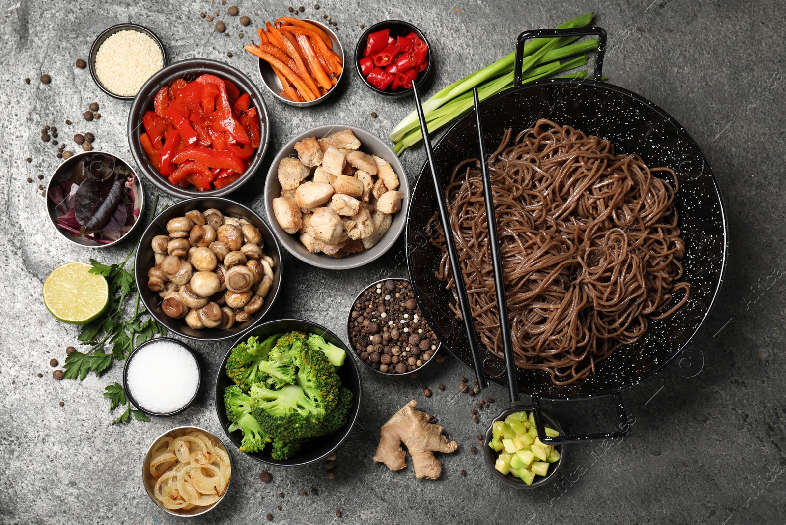 Photo of Wok with noodles, chicken and other products on grey table, flat lay