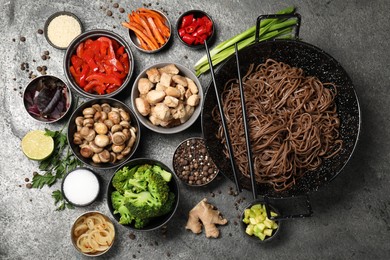 Wok with noodles, chicken and other products on grey table, flat lay