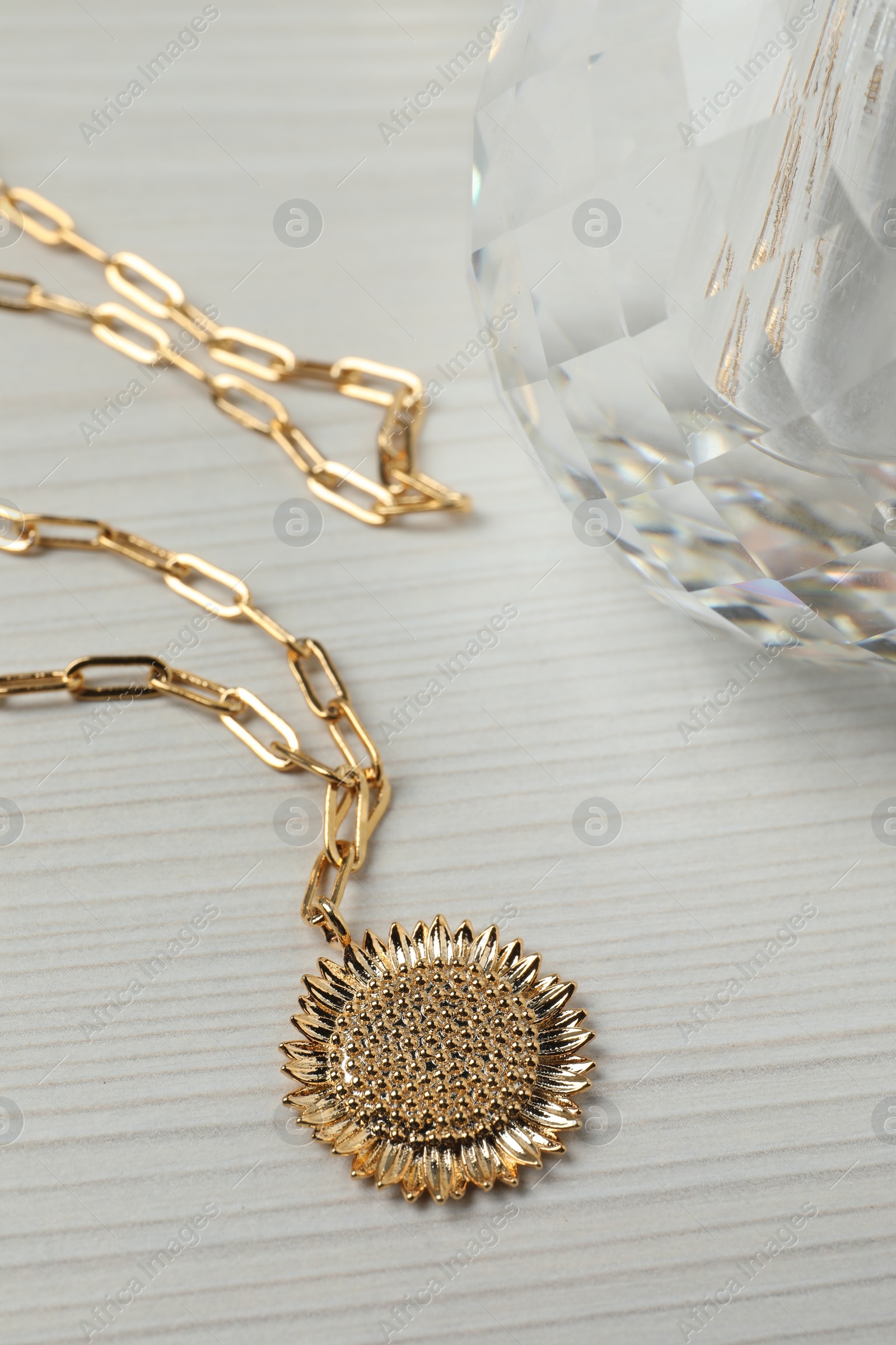 Photo of Necklace and bottle of perfume on white wooden table, closeup