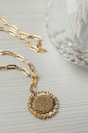 Photo of Necklace and bottle of perfume on white wooden table, closeup