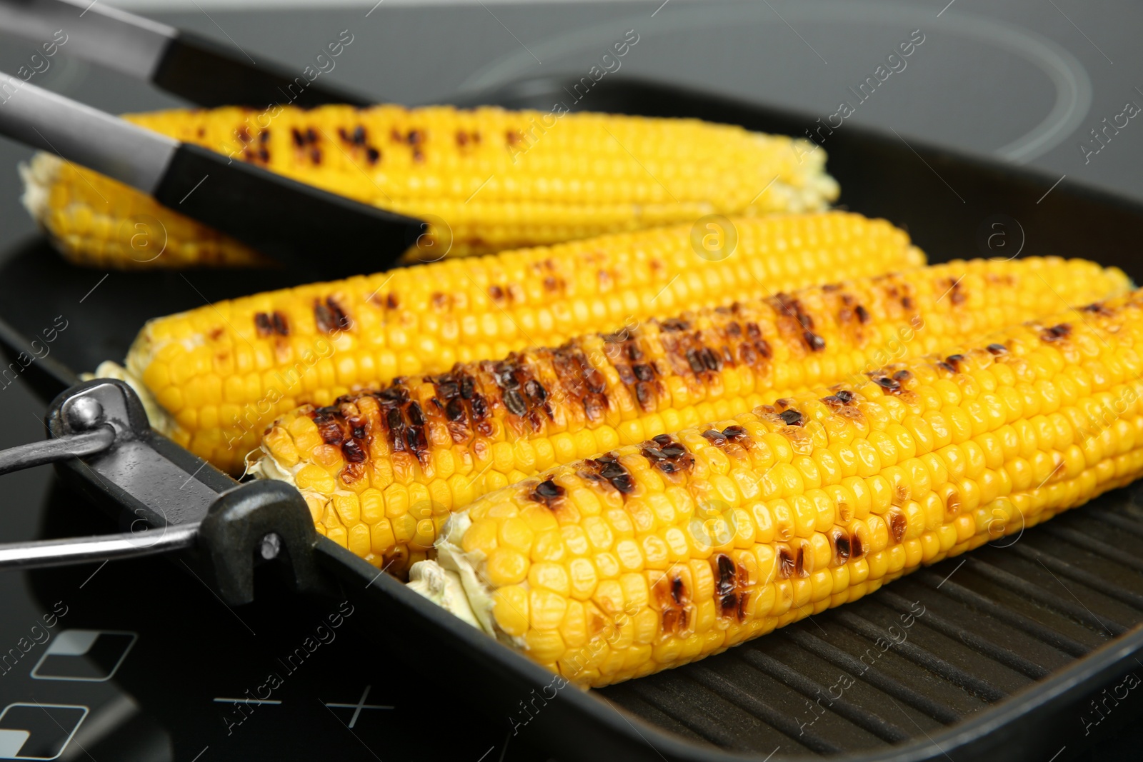 Photo of Cooking fresh corn cobs on grill pan, closeup