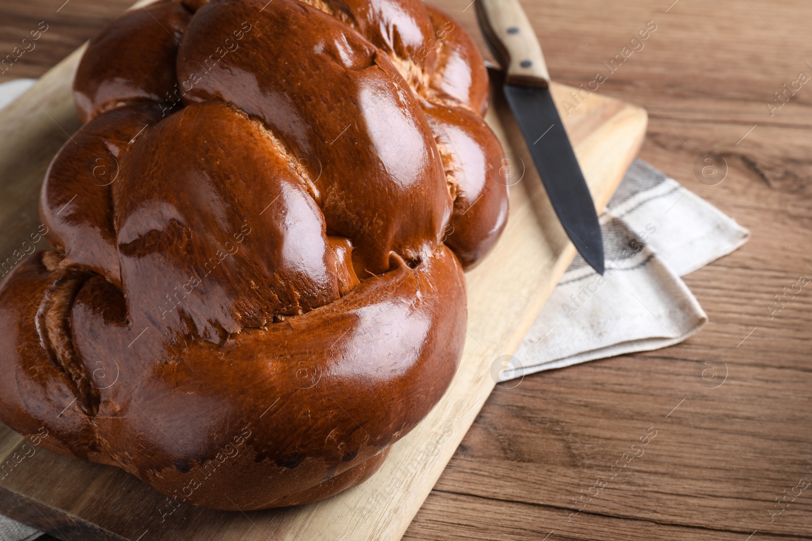 Photo of Closeup view of homemade braided bread on wooden table, space for text. Traditional Shabbat challah