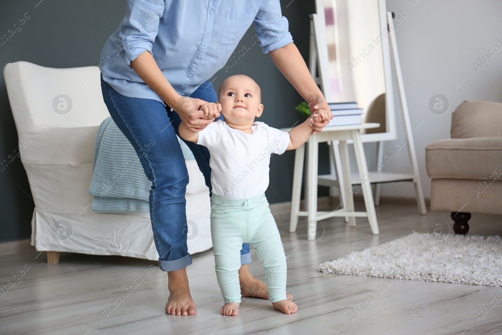 Photo of Baby taking first steps with mother's help at home