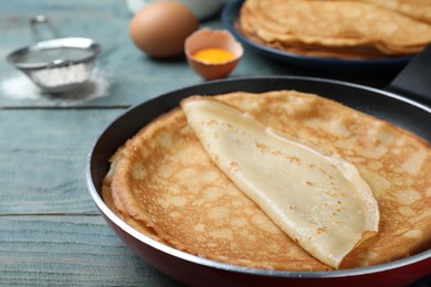 Photo of Delicious thin pancakes on blue wooden table, closeup