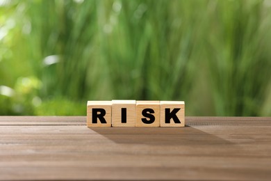 Photo of Cubes with word Risk on wooden table
