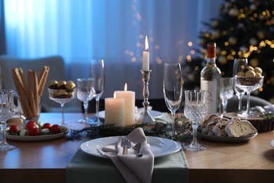 Photo of Christmas table setting with festive decor and dishware in room