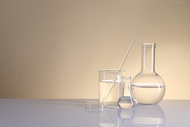 Photo of Laboratory analysis. Different glassware on table against beige background, space for text