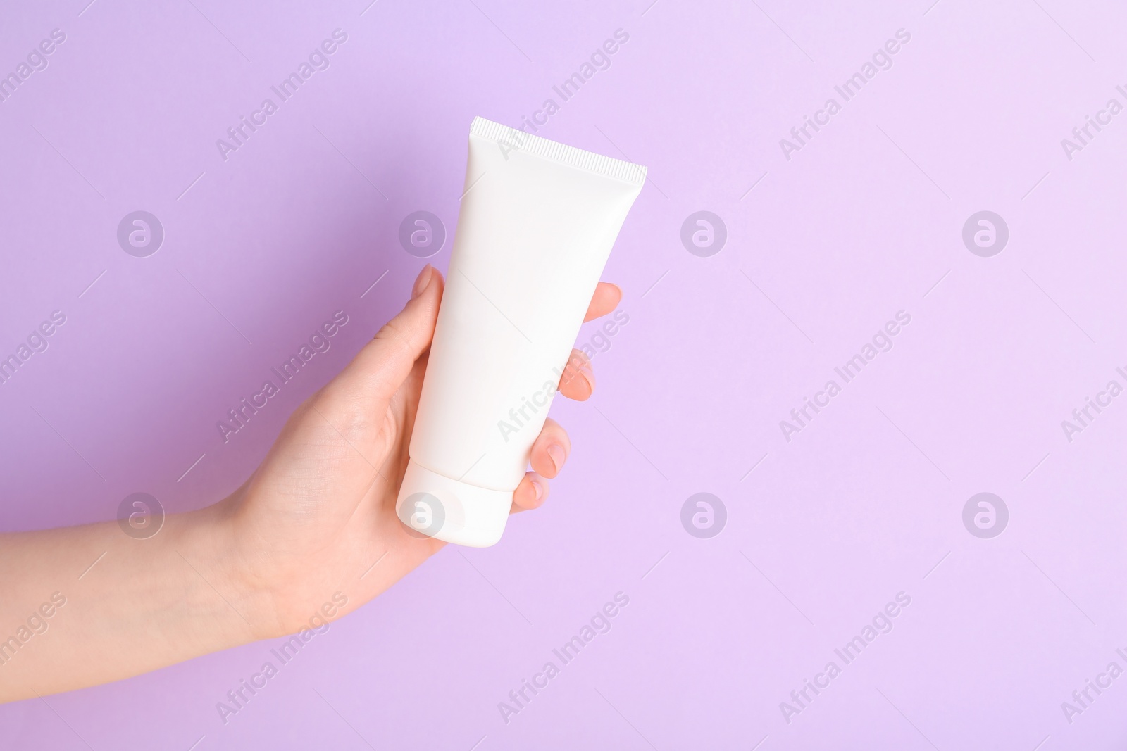 Photo of Woman with tube of cream on lilac background, closeup