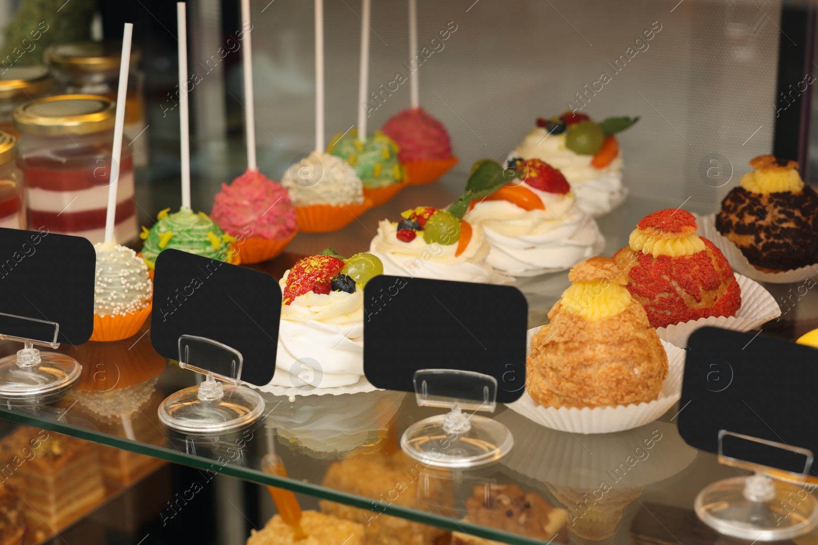 Photo of Showcase with different tasty desserts in store, closeup