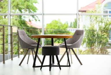 Stylish room interior with round table and comfortable chairs