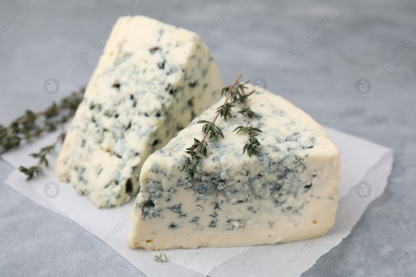 Photo of Tasty blue cheese with thyme on grey table, closeup