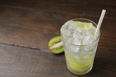 Glass of refreshing drink and cut kiwi on wooden table, closeup. Space for text