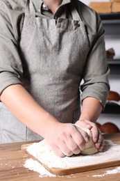 Man kneading dough at table in kitchen, closeup