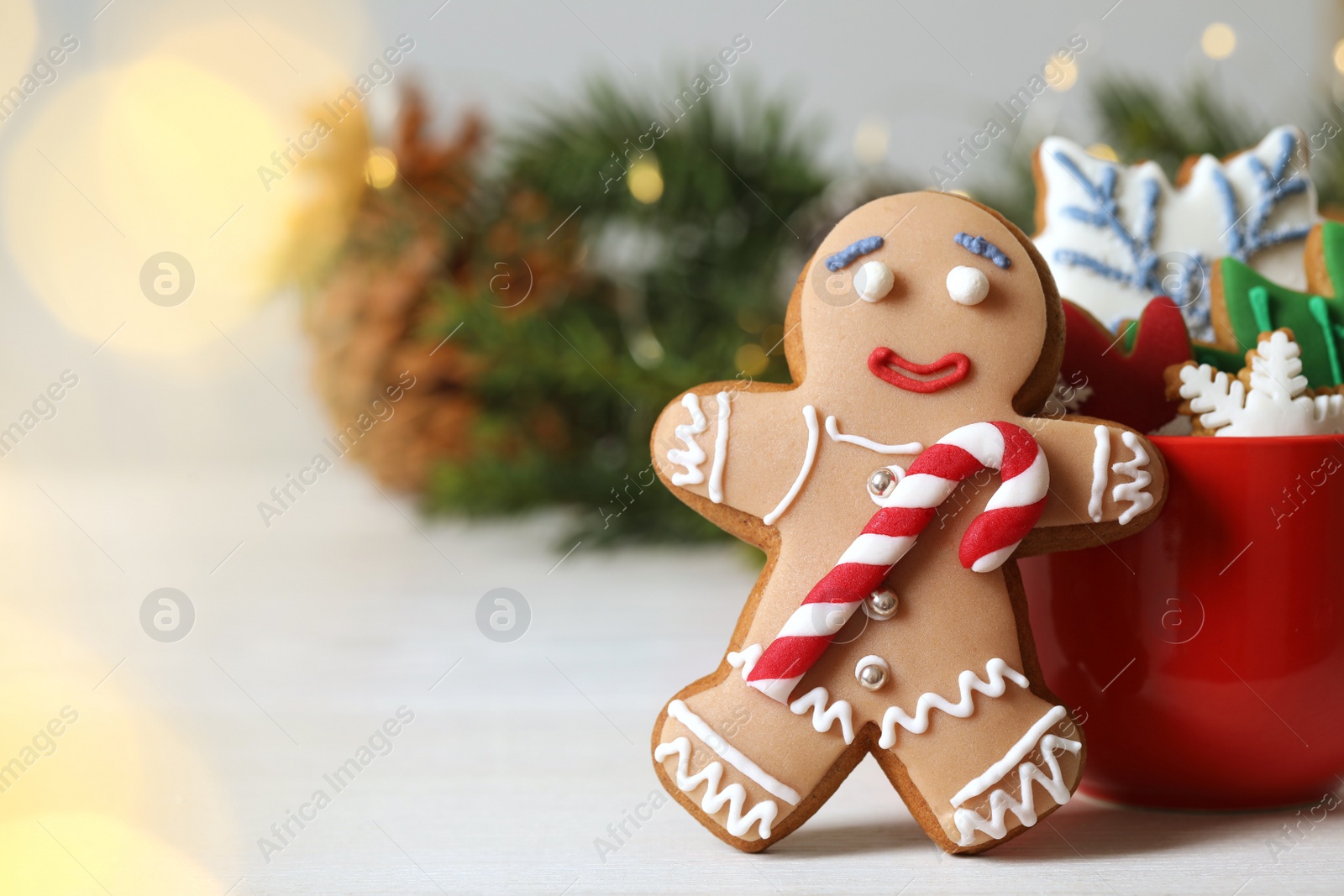 Photo of Gingerbread man and delicious homemade Christmas cookies on white wooden table against blurred festive lights. Space for text