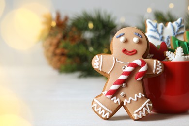 Photo of Gingerbread man and delicious homemade Christmas cookies on white wooden table against blurred festive lights. Space for text