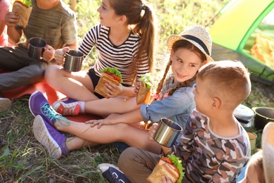 Photo of Little children eating sandwiches outdoors. Summer camp