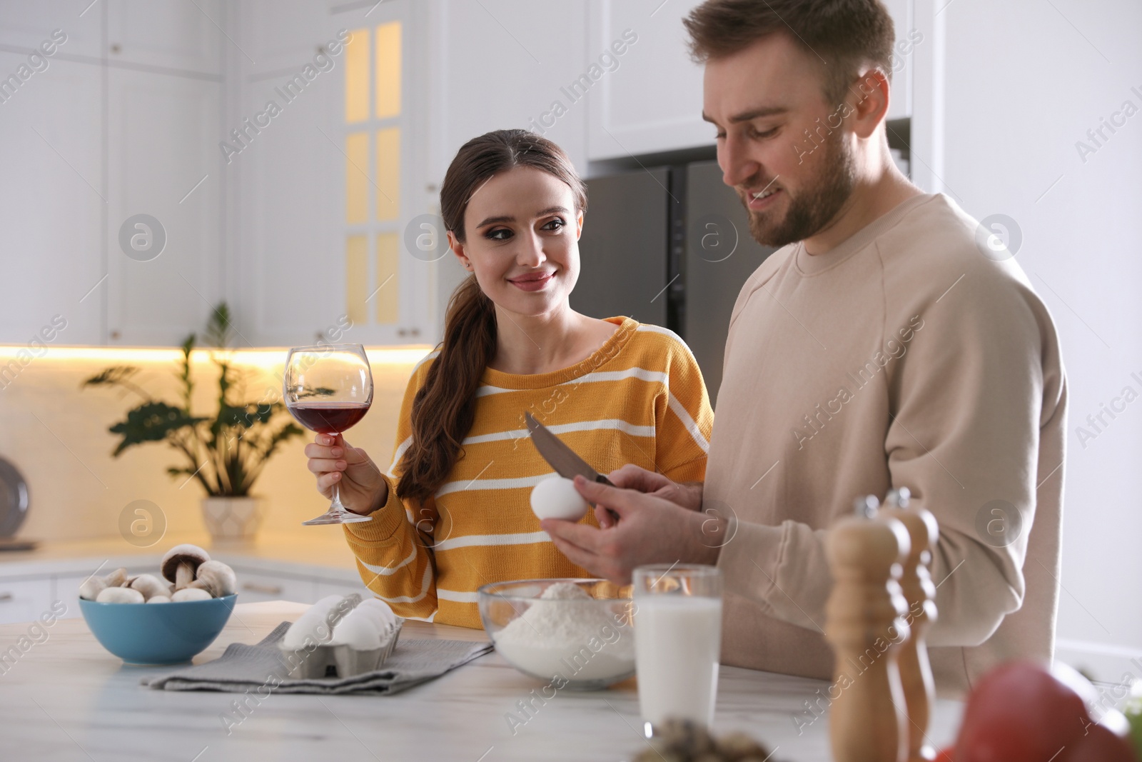 Photo of Lovely young couple cooking dough together in kitchen