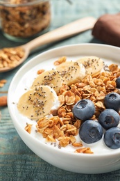 Bowl of yogurt with blueberries, banana and oatmeal on wooden table, closeup