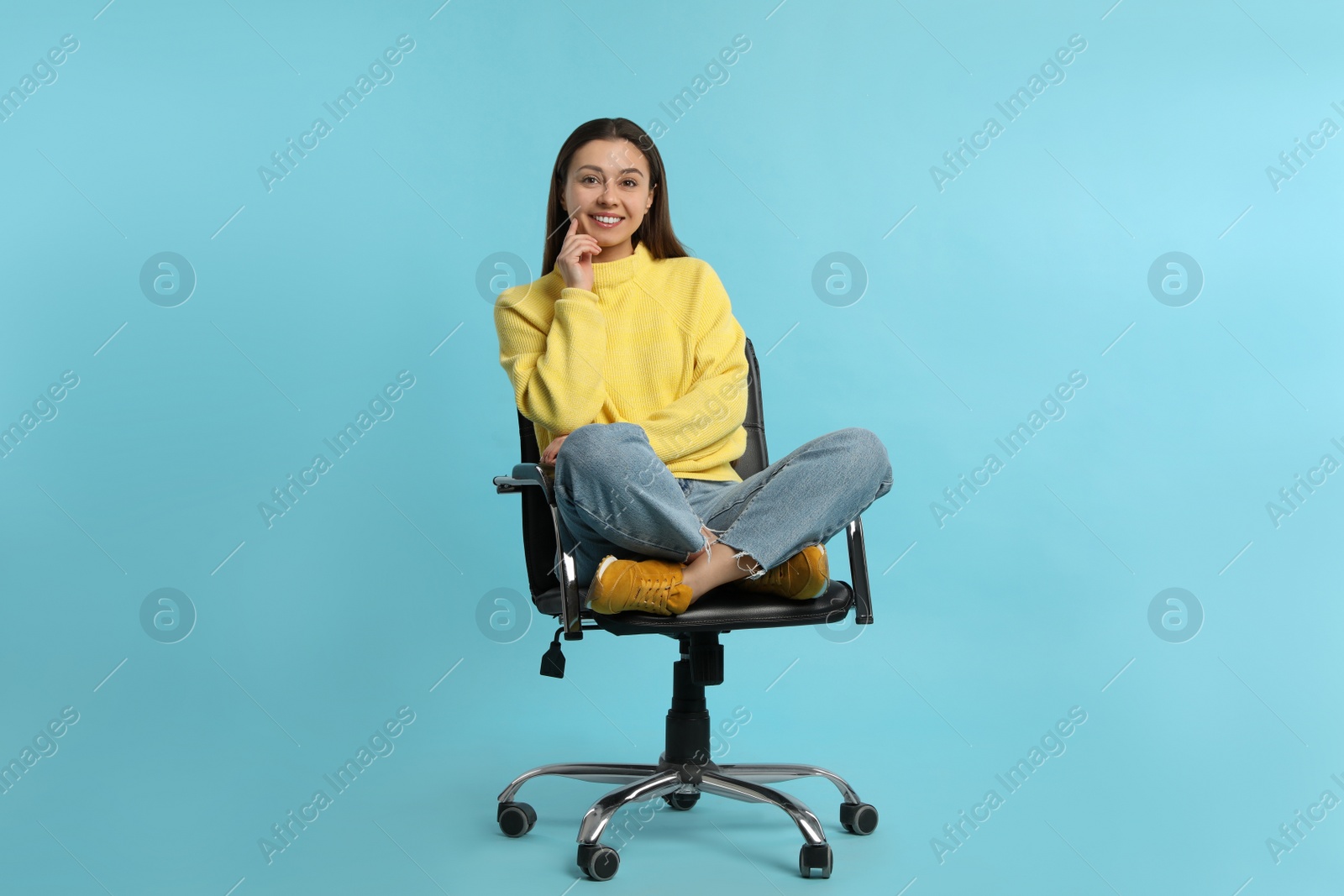 Photo of Young woman sitting in comfortable office chair on turquoise background