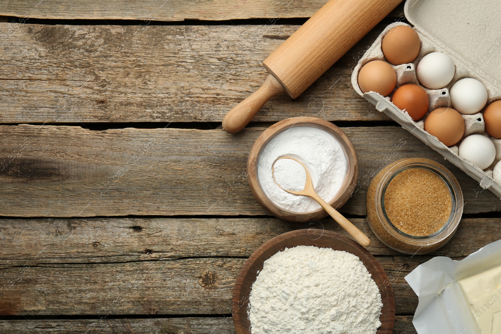 Photo of Ingredients for making dough and rolling pin on wooden table, flat lay. Space for text