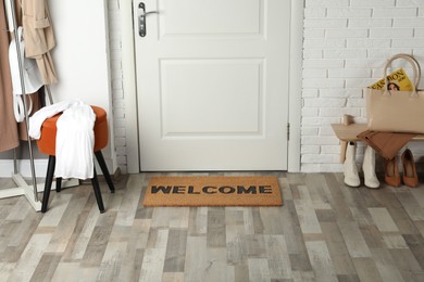 Photo of Doormat with word Welcome on wooden floor in hall