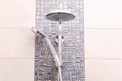Shower heads on tiled wall in bathroom