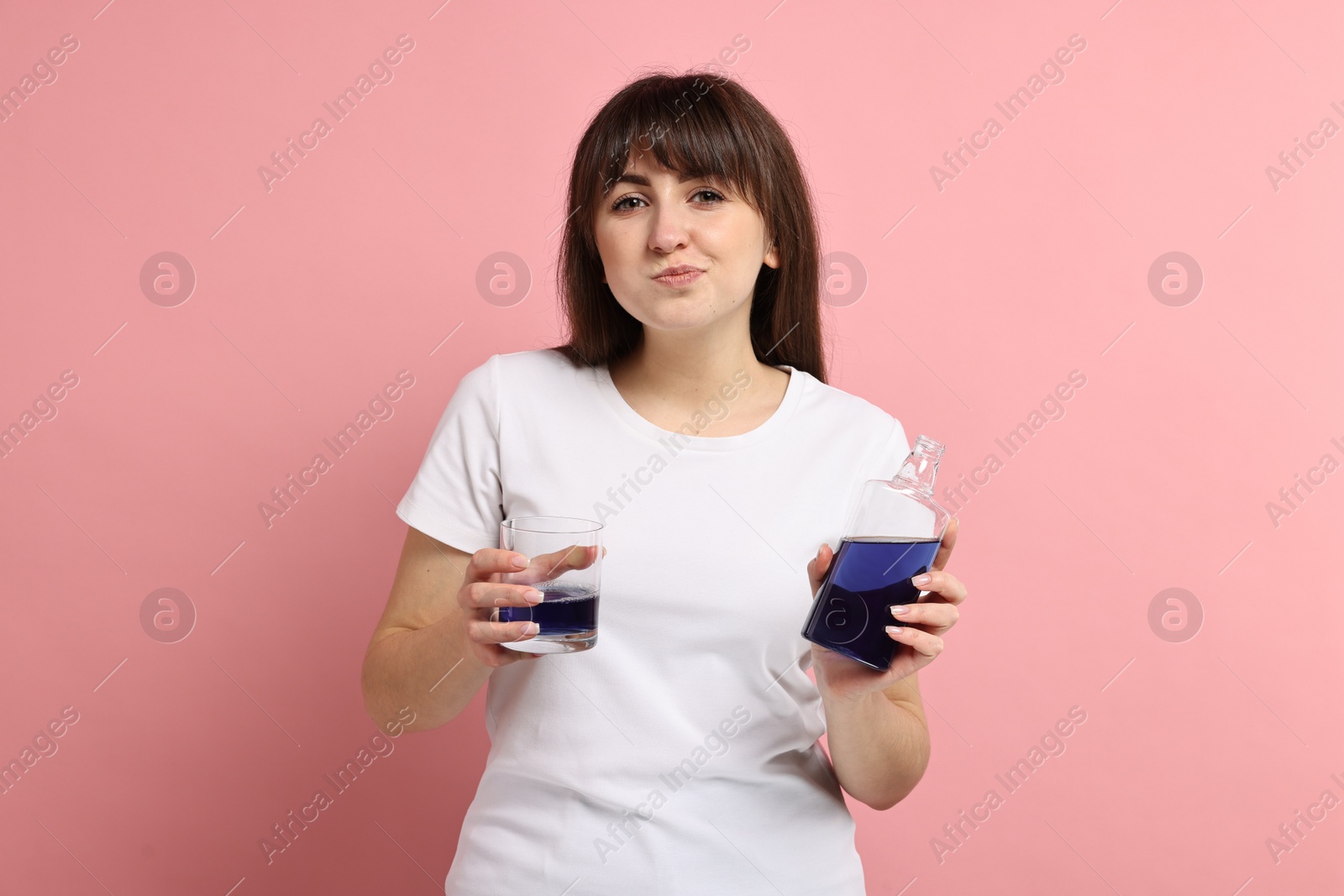 Photo of Young woman using mouthwash on pink background