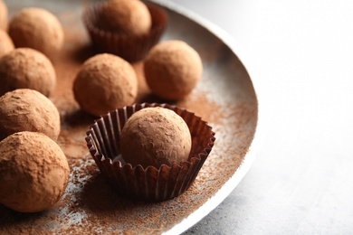 Plate with tasty chocolate truffles on grey table, space for text