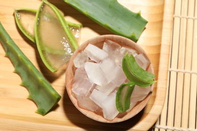 Aloe vera gel and slices of plant on bamboo mat, top view