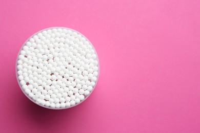 Photo of Many cotton buds in container on pink background, top view. Space for text