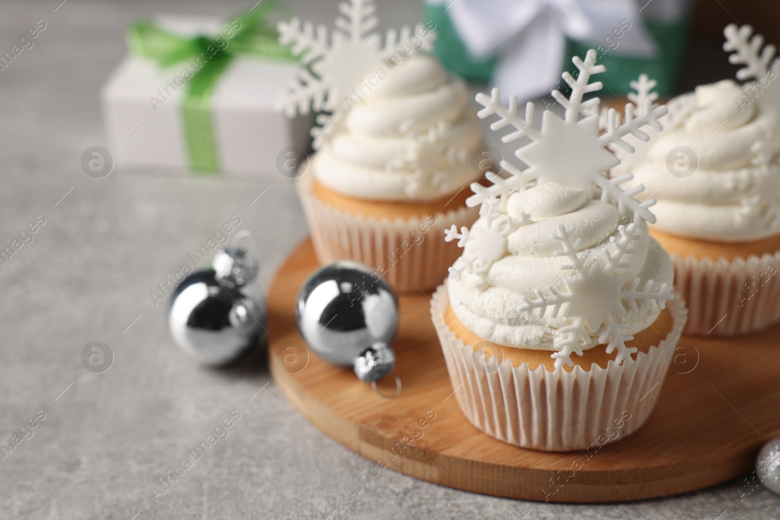 Photo of Tasty Christmas cupcakes with snowflakes on grey table. Space for text