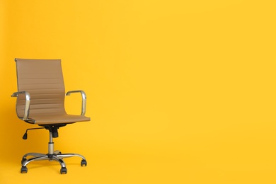 Photo of Modern office chair on yellow background. Space for text