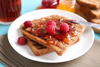 Image of Tasty toast with raspberry jam and fresh berries for breakfast on table, closeup