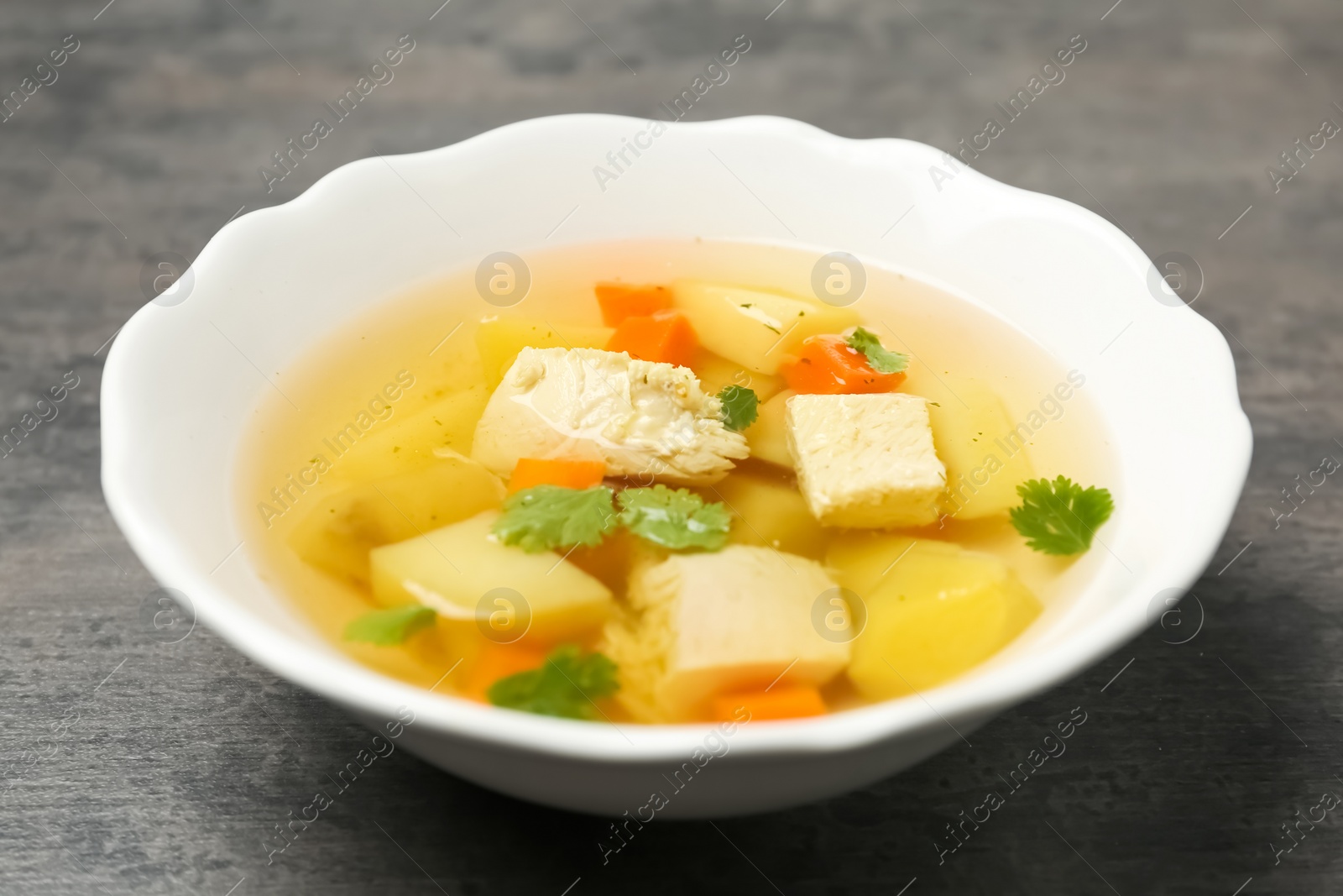 Photo of Dish with fresh homemade chicken soup on grey table