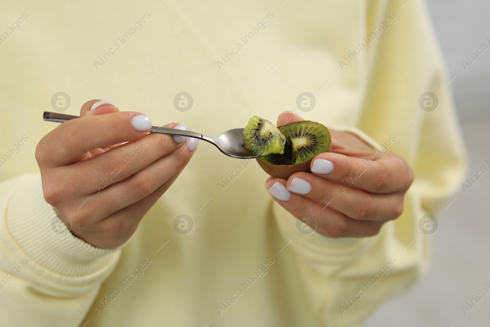 Photo of Woman eating kiwi with spoon, closeup view