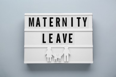 Photo of Lightbox with words Maternity Leave and figures of family on light grey background, top view