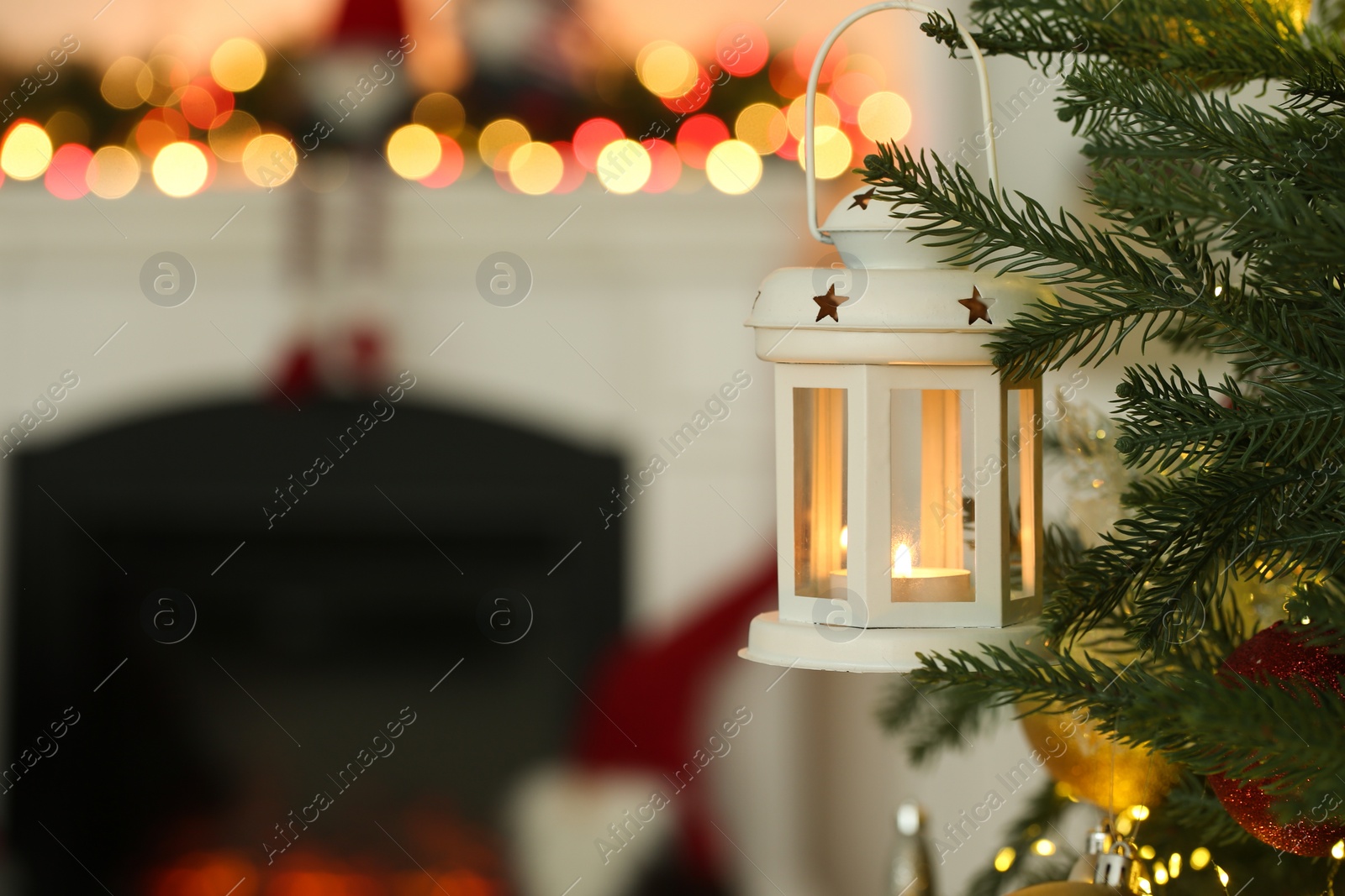 Photo of Christmas lantern with burning candle on fir tree indoors, closeup. Space for text