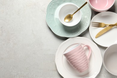 Photo of Beautiful ceramic dishware, cup and cutlery on light grey table, flat lay. Space for text