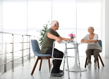 Elderly woman and her husband with walking frame indoors