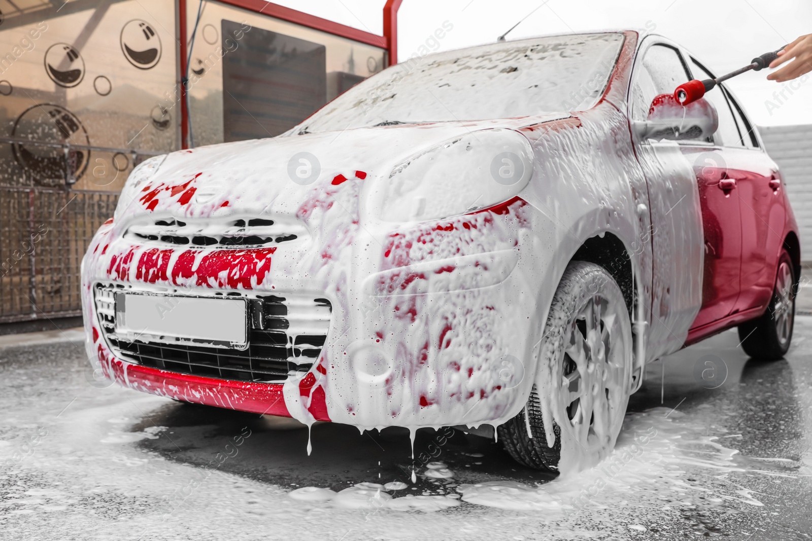 Photo of Foaming red auto at car wash. Cleaning service