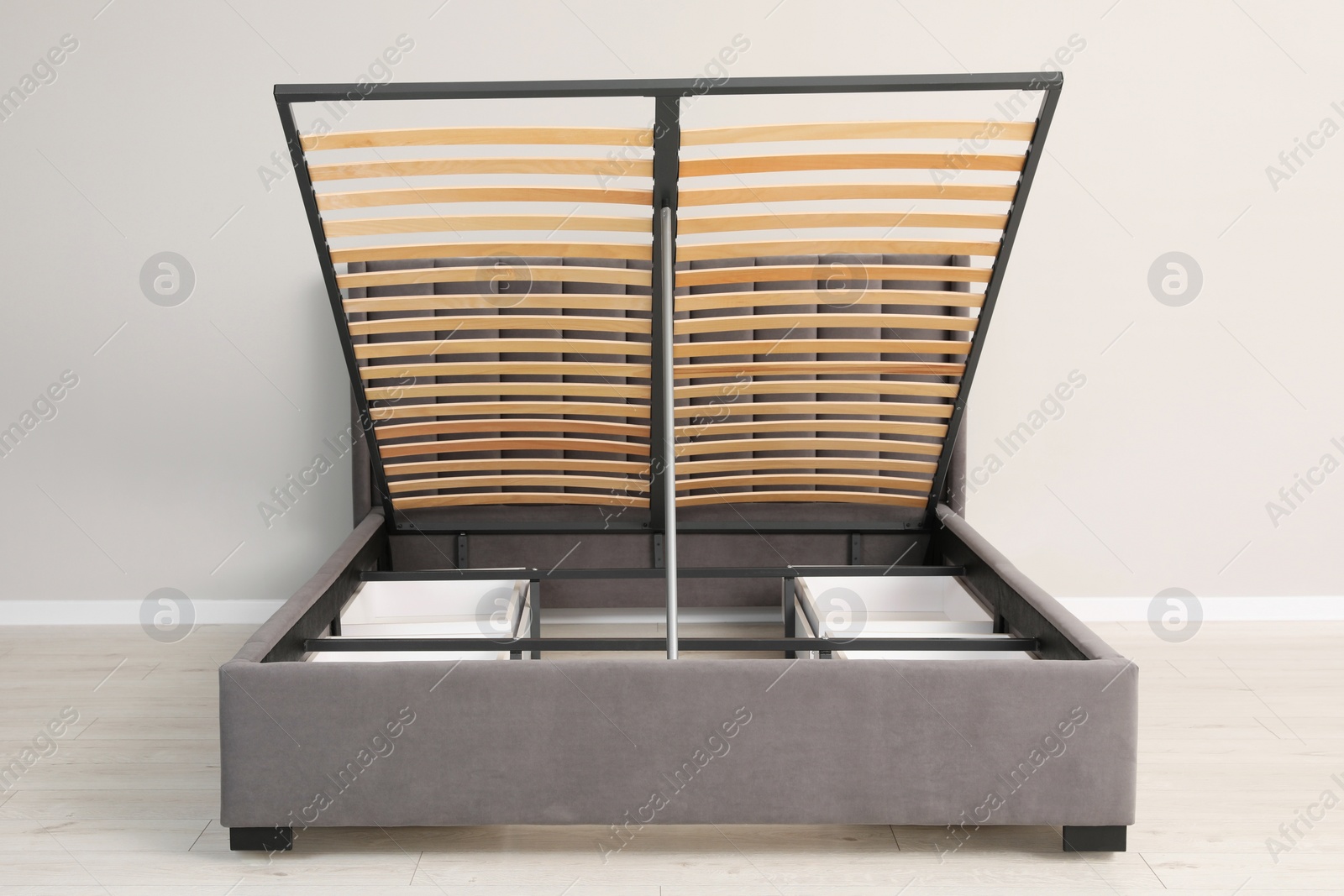 Photo of Comfortable bed with storage space for bedding under lifted slatted base in room