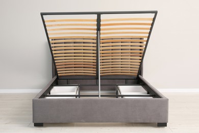 Photo of Comfortable bed with storage space for bedding under lifted slatted base in room