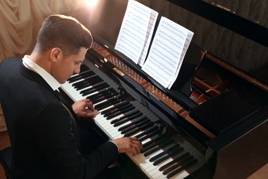 Man playing piano indoors, above view. Talented musician