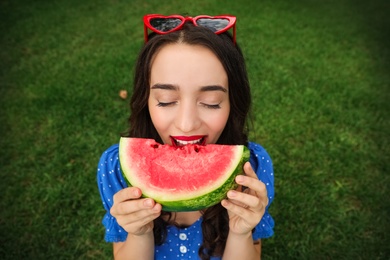 Photo of Beautiful young woman with watermelon on green grass outdoors