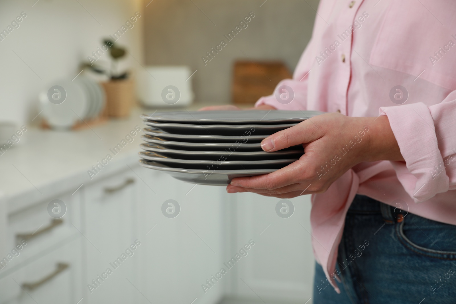 Photo of Woman holding plates in kitchen, closeup view