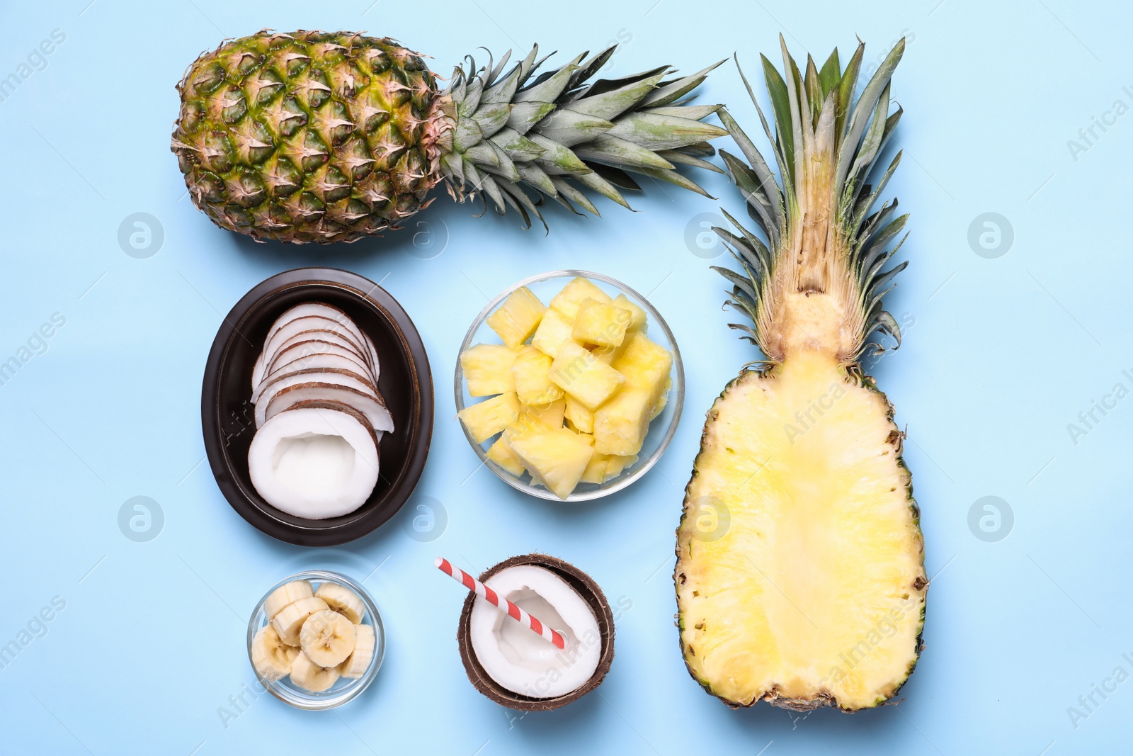 Photo of Flat lay composition with pineapples and coconuts on light blue background